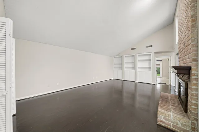 an empty room with wooden floor and fireplace
