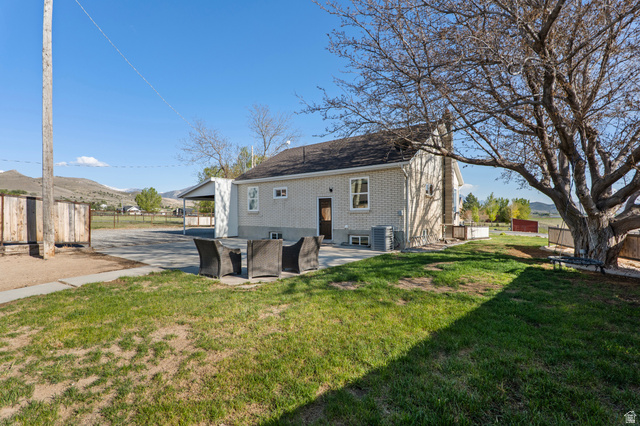 115 East 1600th Street North Santaquin, UT 84655 - Photo 33 of 52 Rear exterior featuring a spacious paved patio, a large mature tree, and a grassy area