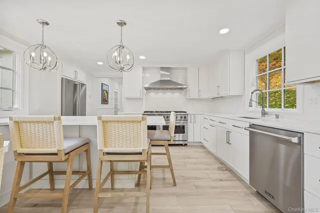 a kitchen with stainless steel appliances granite countertop a stove oven a sink dishwasher and white cabinets with wooden floor