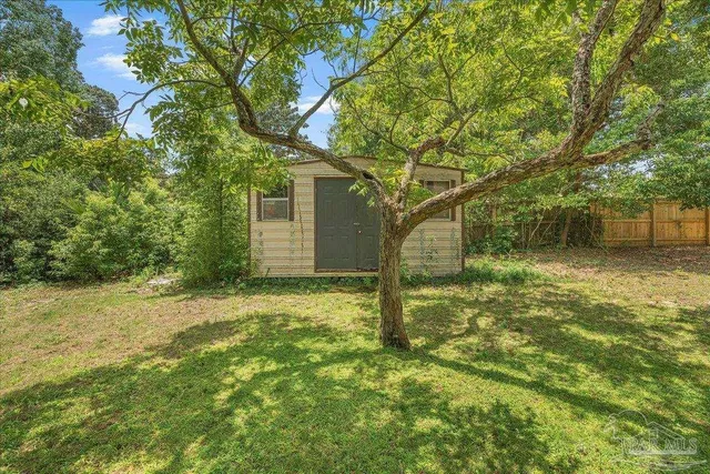 a backyard of a house with lots of plants and large tree