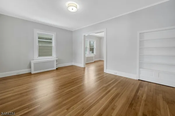 a view of an empty room with wooden floor and a window