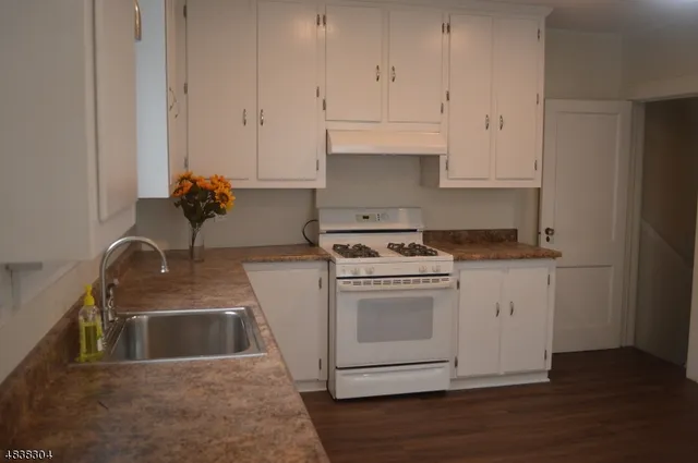 a kitchen with granite countertop white cabinets and white appliances