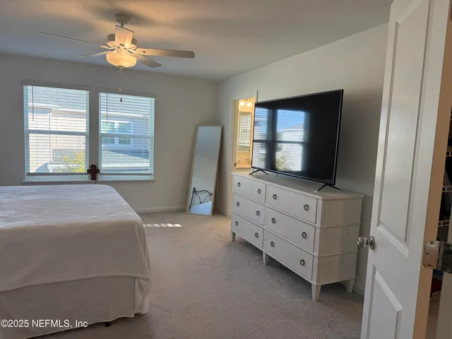 a bedroom with a bed and a flat tv screen on dresser