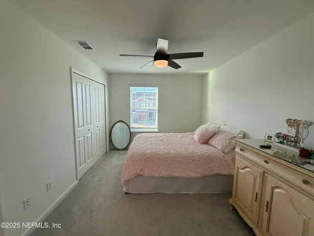 a bedroom with a bed and a large mirror next to a window