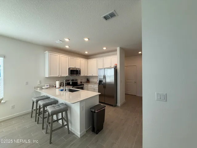 a kitchen with a refrigerator a stove top oven a sink with a dining table and chairs