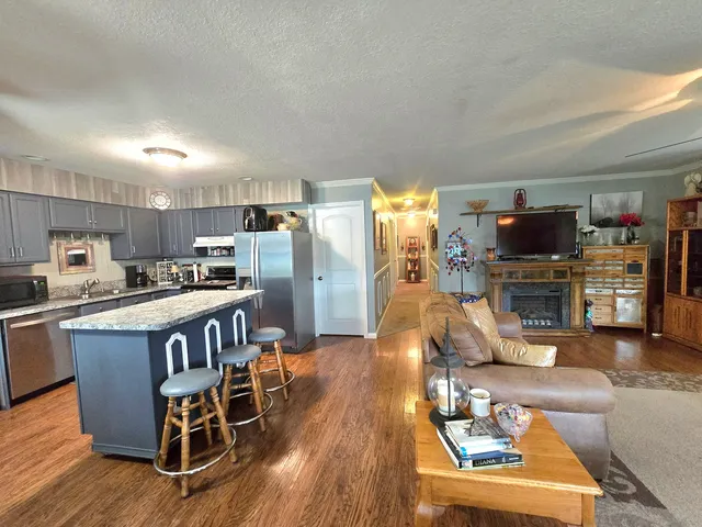 a living room with stainless steel appliances furniture a flat screen tv and kitchen view