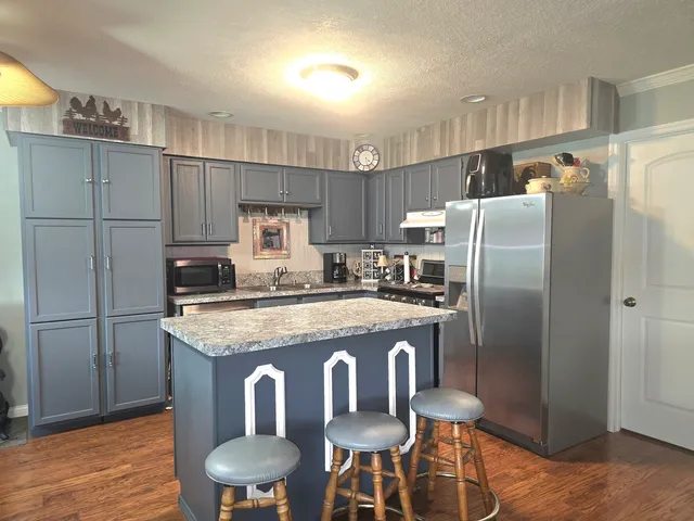 a kitchen with stainless steel appliances granite countertop a refrigerator a sink a stove a dining table and chairs