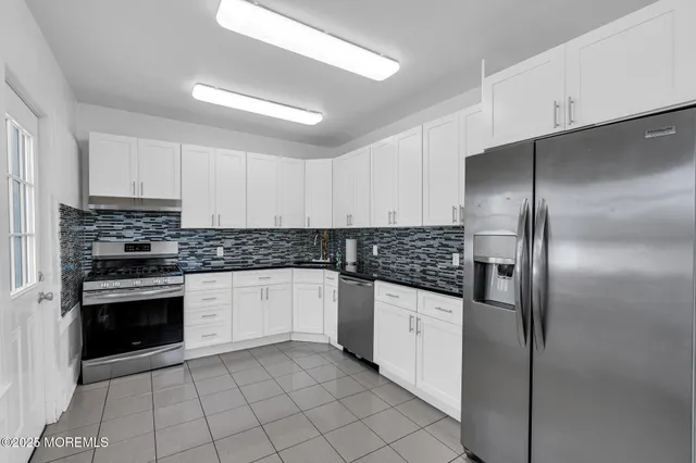 a kitchen with granite countertop a refrigerator and white stainless steel appliances
