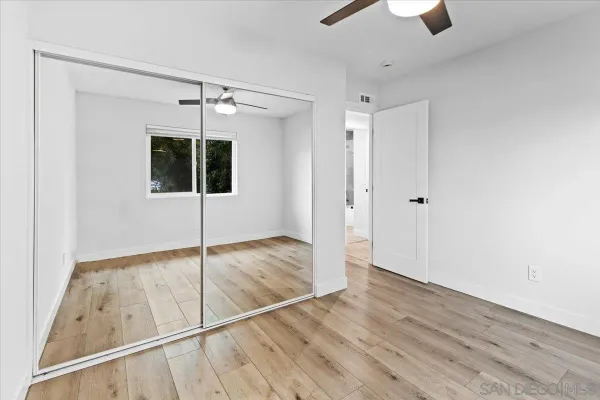 a view of empty room with wooden floor and fan
