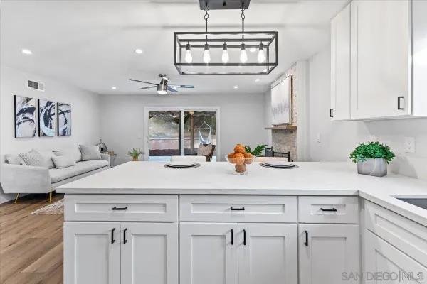 a kitchen with a sink dishwasher and white cabinets with wooden floor