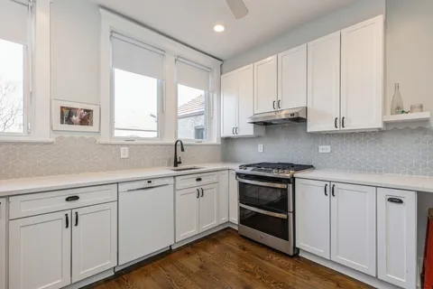 a kitchen with granite countertop white cabinets and a sink