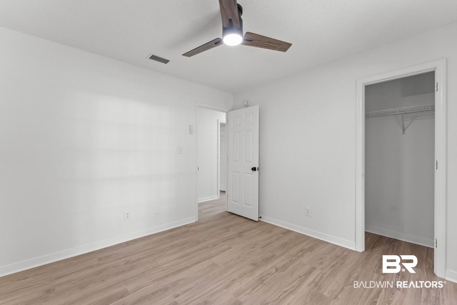 10251 Windmill Road Fairhope, AL 36532 - Photo 33 of 44 Unfurnished bedroom featuring light wood-style flooring, a closet, a ceiling fan, and a walk in closet