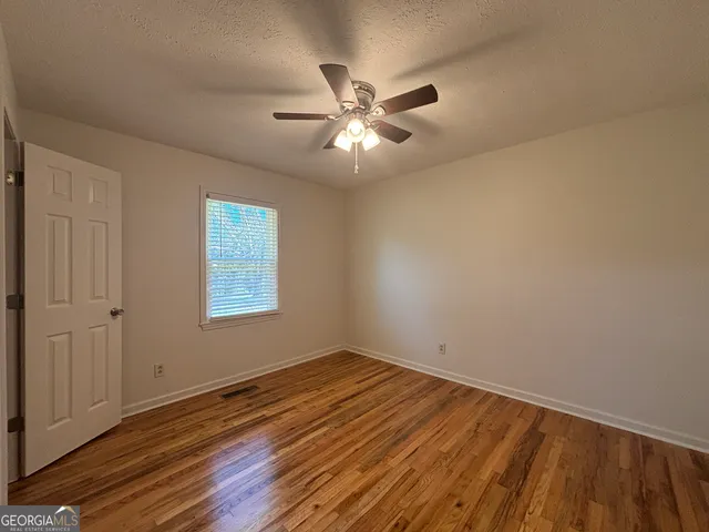 a view of a room with wooden floor and a ceiling fan