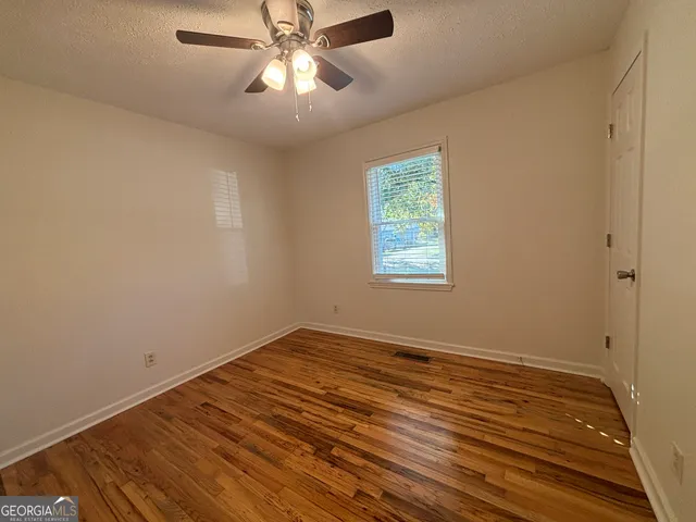 a view of an empty room with wooden floor and a window