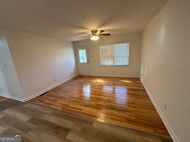 a view of room with window ceiling fan and hardwood floor