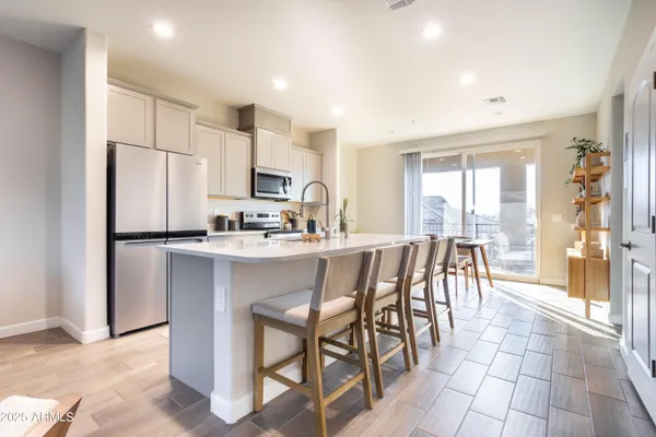 a kitchen with stainless steel appliances a refrigerator a stove a sink dishwasher with a dining table and chairs