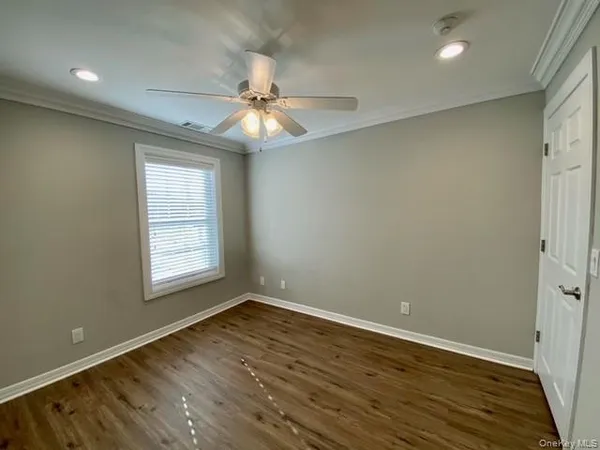an empty room with wooden floor fan and windows
