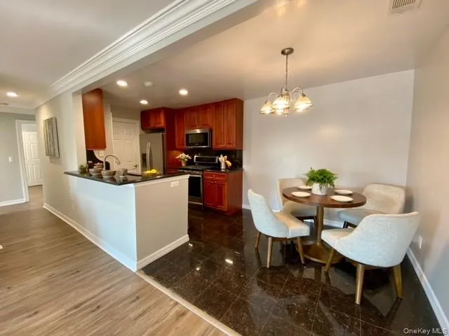 a kitchen with stainless steel appliances kitchen island granite countertop a table chairs and a refrigerator
