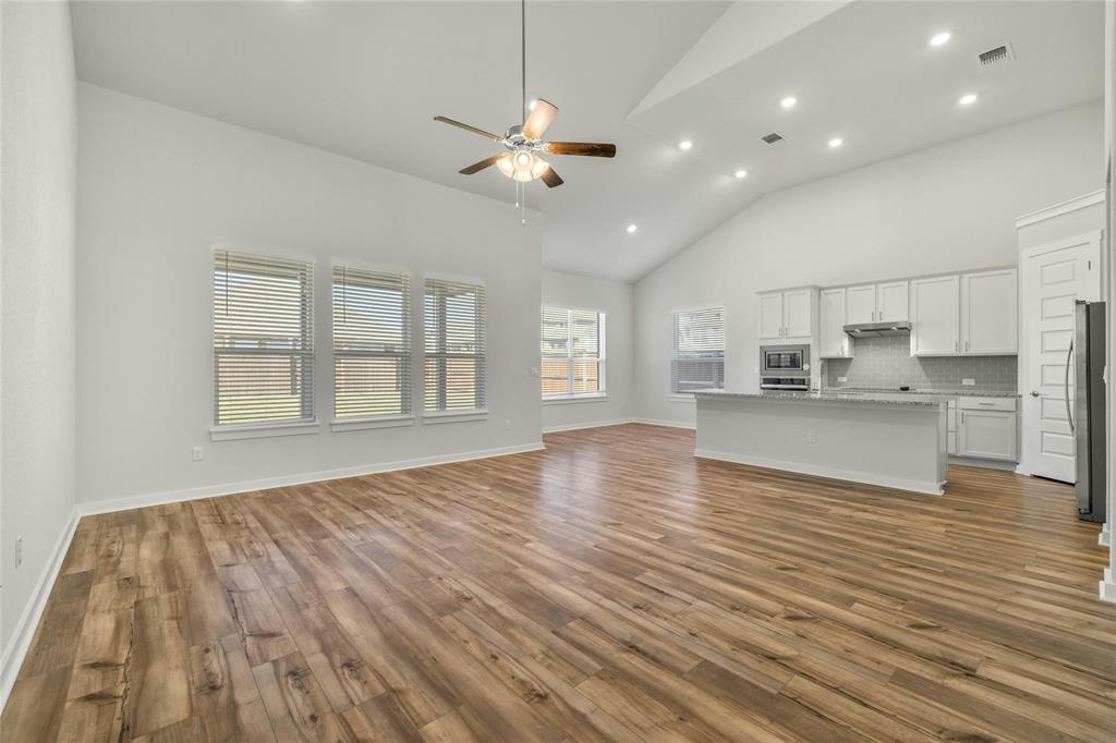 113 Shadow Oak Cove Georgetown, TX 78628 - Photo 5 of 40 An open-concept living space with soaring vaulted ceilings and rich wood flooring flows into a sleek, well-equipped kitchen.
