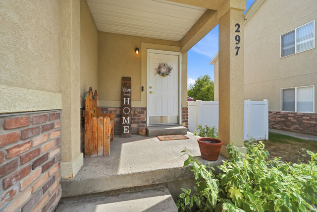 297 West Bricker Road Draper, UT 84020 - Photo 3 of 44 Covered concrete porch entry featuring a white door, brick facade accents, and durable stucco siding