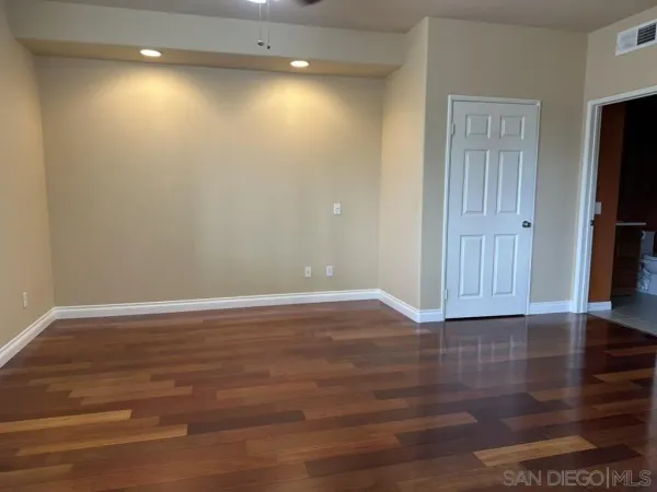 a view of an empty room with a window and wooden floor