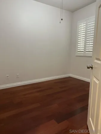 an empty room with wooden floor and entrance