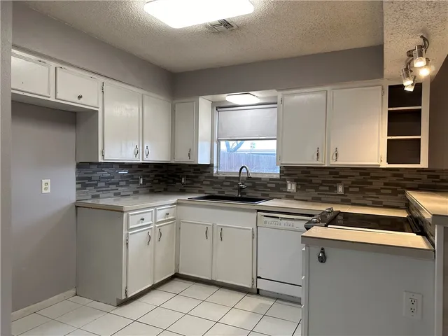a kitchen with white cabinets appliances and a sink