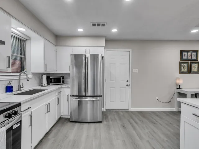 a kitchen with a refrigerator a sink and wooden floor