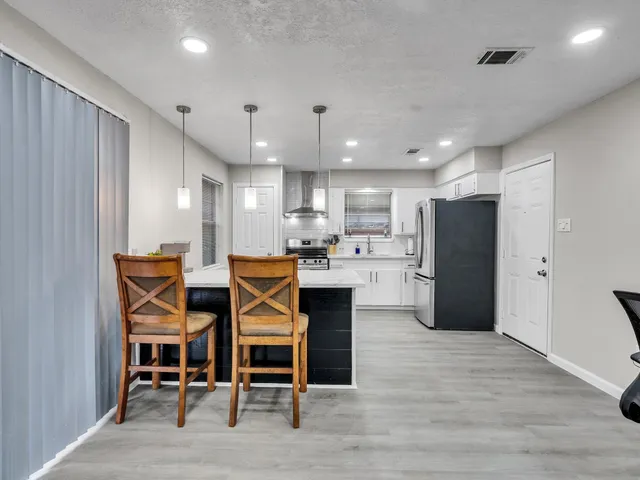 a kitchen with stainless steel appliances kitchen island granite countertop a dining table and chairs in it