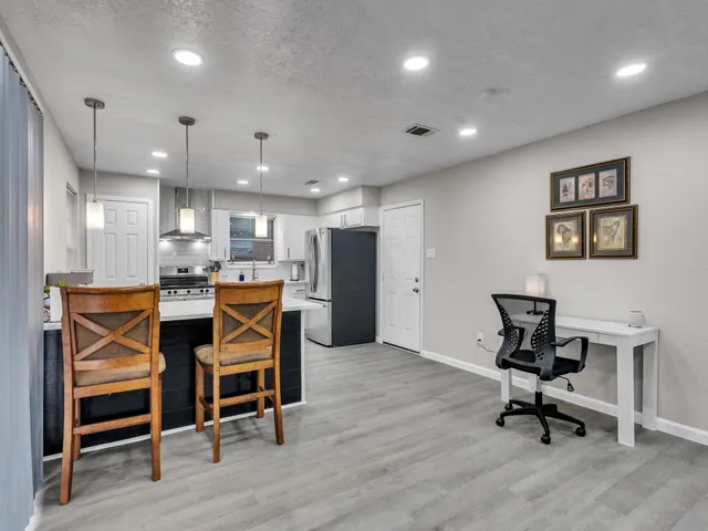 a kitchen with stainless steel appliances kitchen island granite countertop a dining table chairs and sink