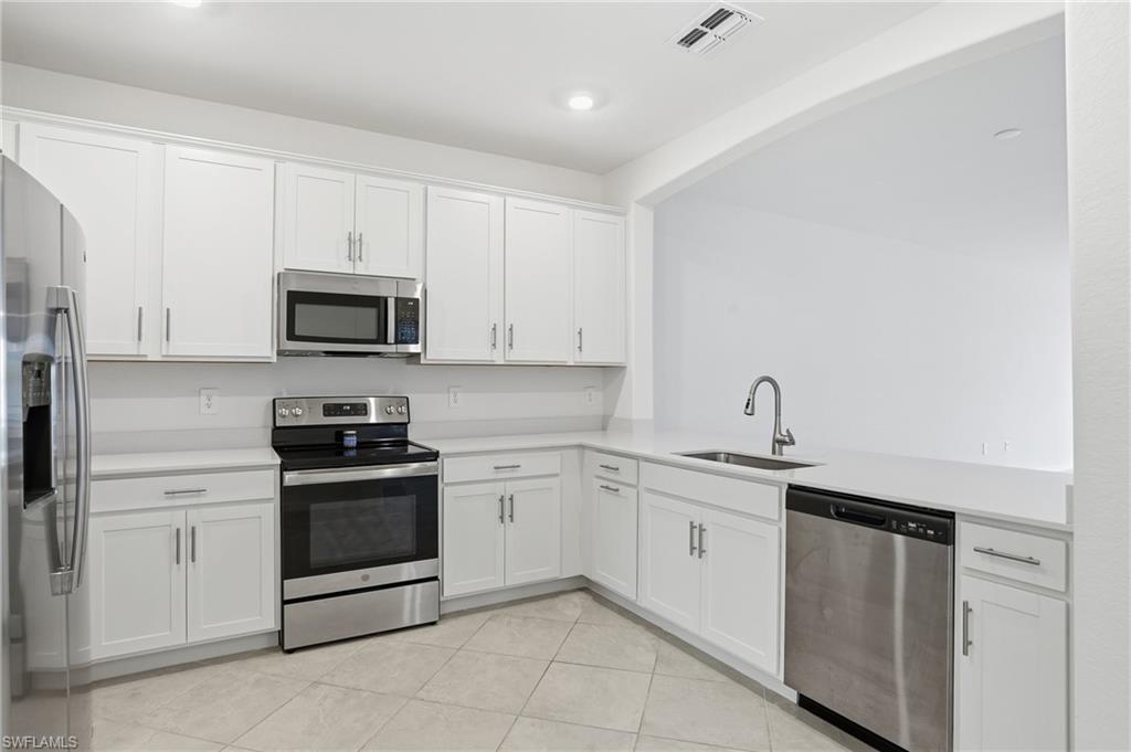 2215 Dragonfruit Way Naples, FL 34120 - Photo 18 of 38 a kitchen with white cabinets stainless steel appliances and a sink