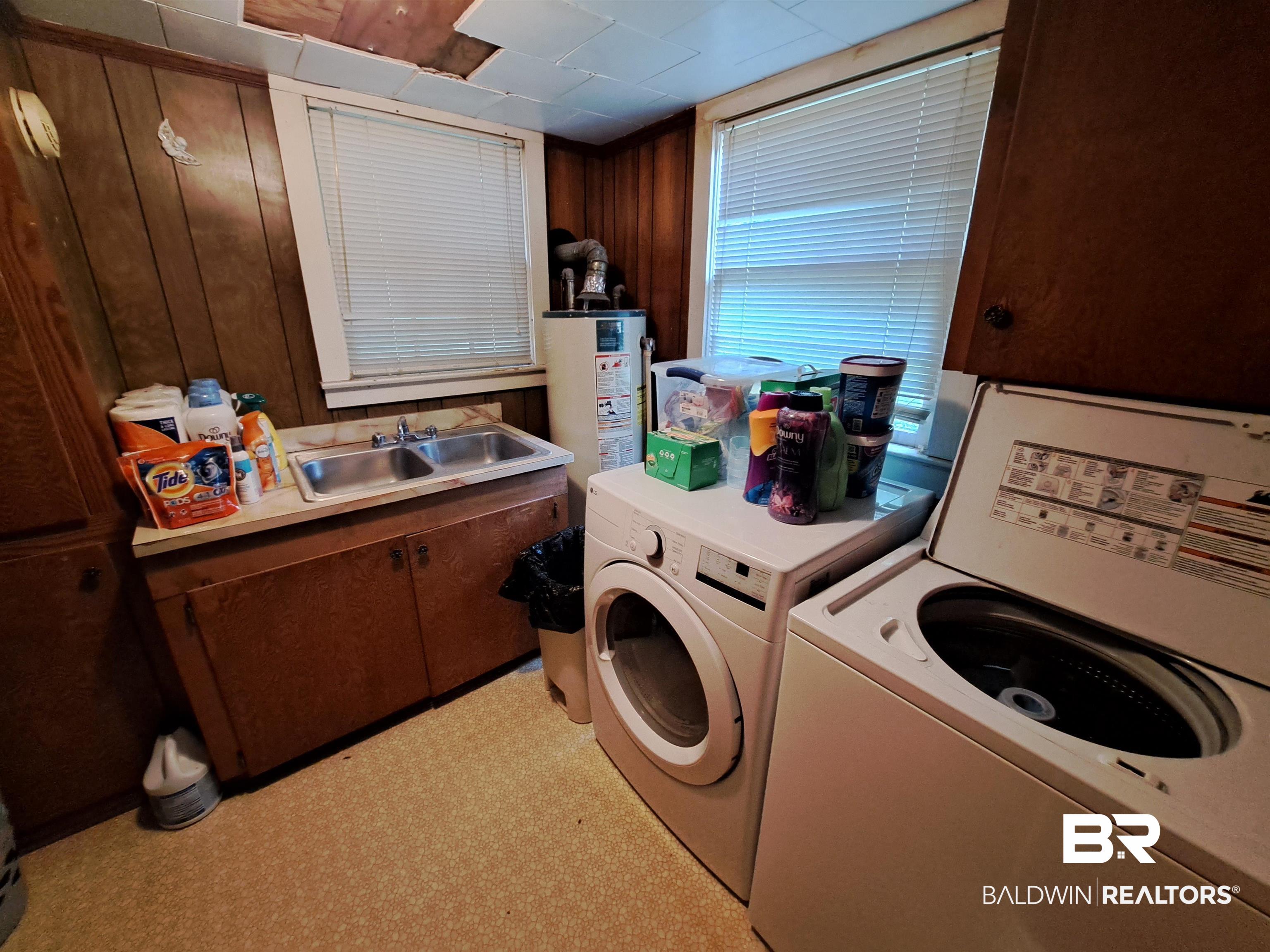 309 Bellview Avenue Evergreen, AL 36401 - Photo 25 of 27 Washroom featuring cabinet space, wooden walls, light floors, independent washer and dryer, and water heater
