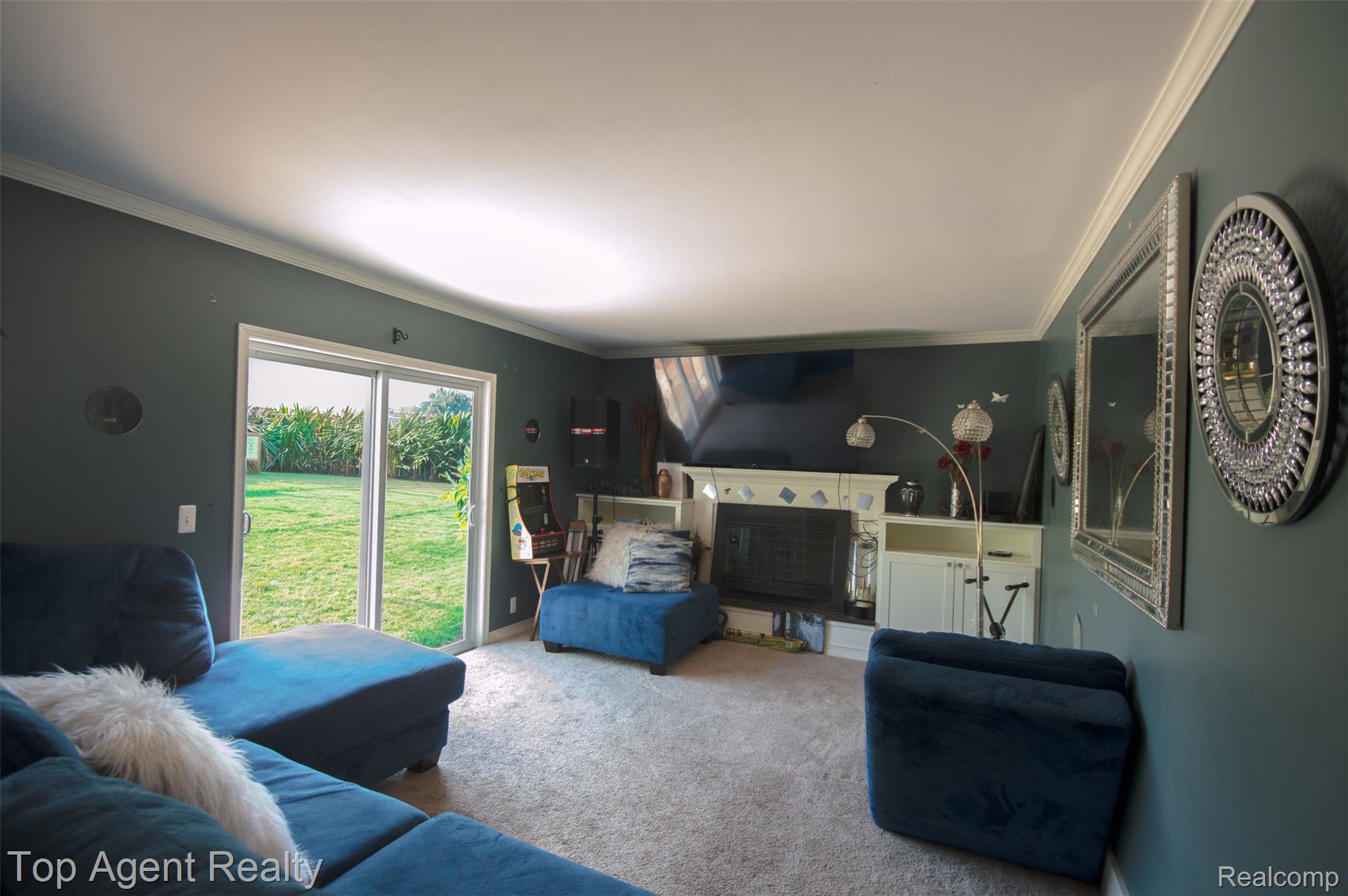 36218 Paddock Drive Clinton Township, MI 48035 - Photo 9 of 22 Spacious living area featuring a fireplace with built-in cabinetry, crown molding, sliding glass doors, and carpet flooring