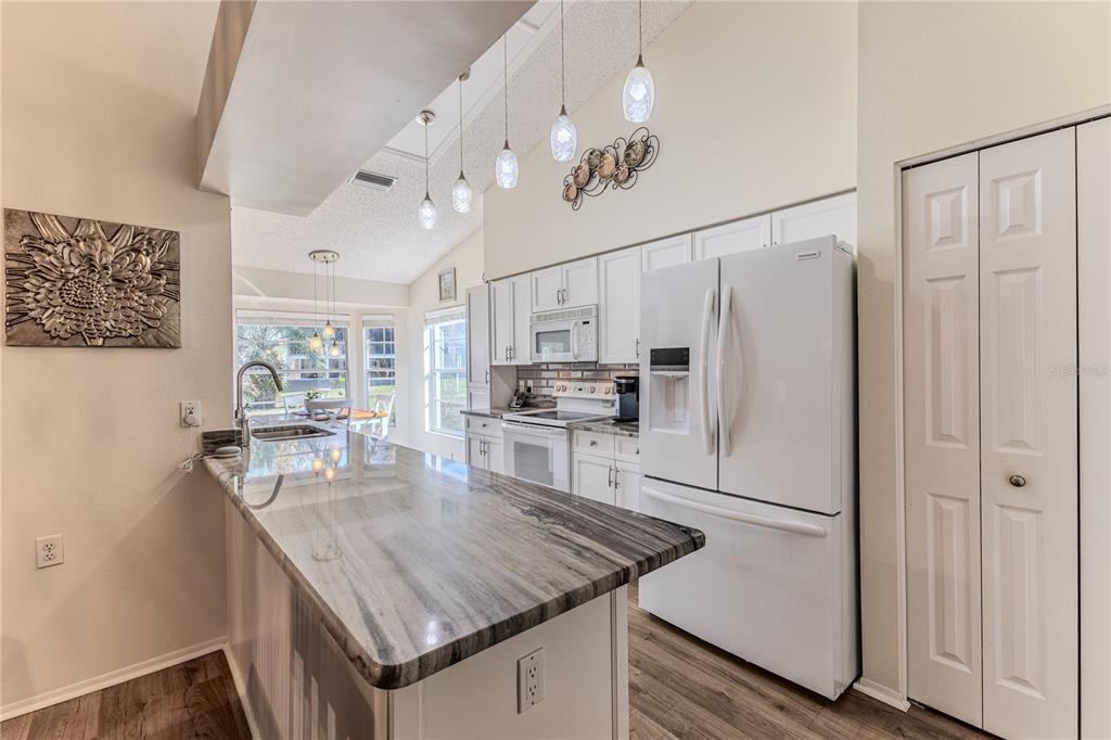 7443 Willowbrook Drive Spring Hill, FL 34606 - Photo 19 of 54 a kitchen with stainless steel appliances granite countertop a refrigerator a sink dishwasher a stove and white cabinets with wooden floor