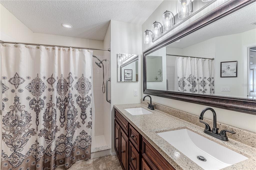 7443 Willowbrook Drive Spring Hill, FL 34606 - Photo 26 of 54 a bathroom with a granite countertop sink a mirror and shower