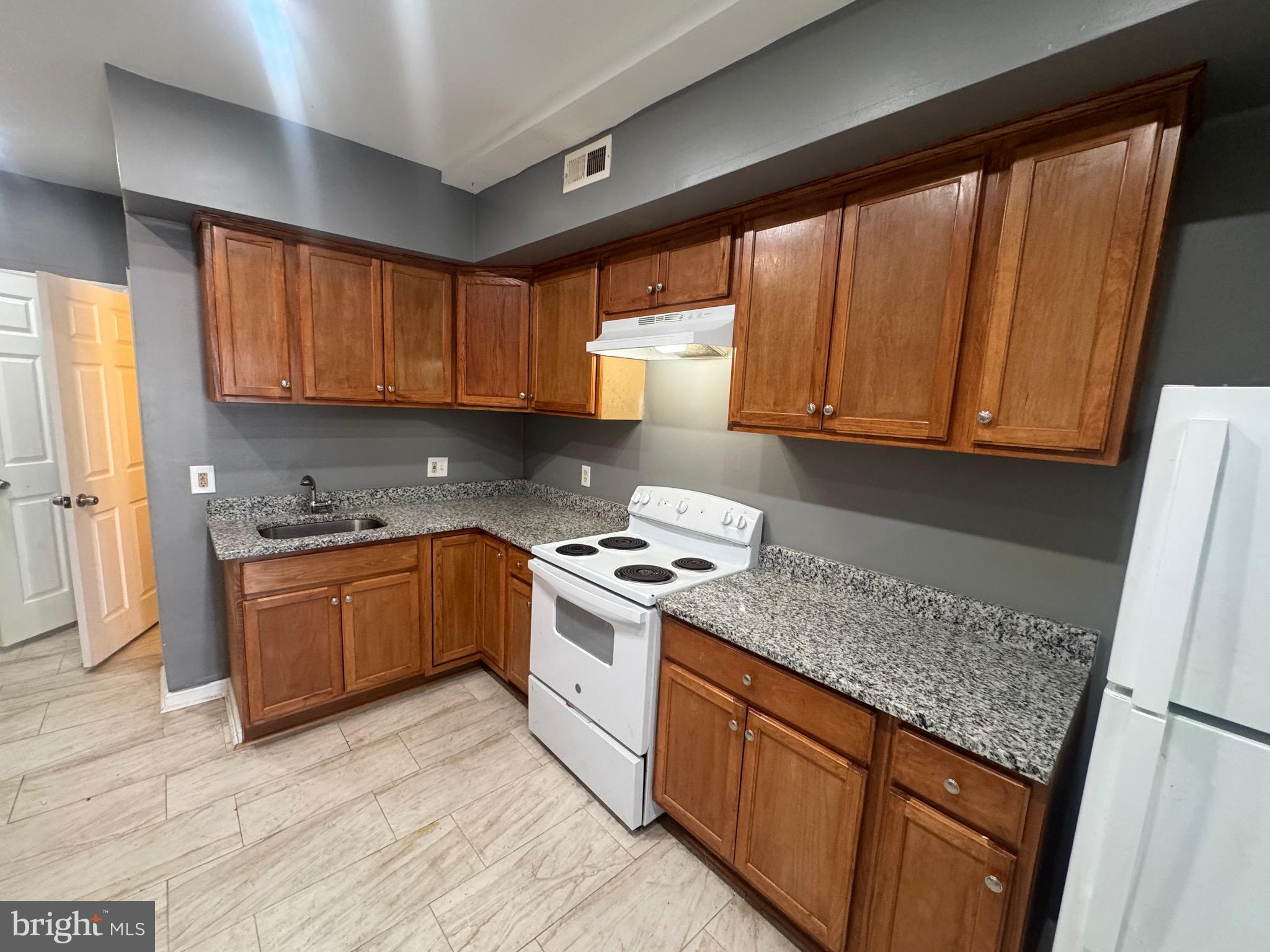 1108 North Bond Street, Unit 1 Baltimore, MD 21213 - Photo 11 of 20 a kitchen with granite countertop wooden cabinets a sink and a stove