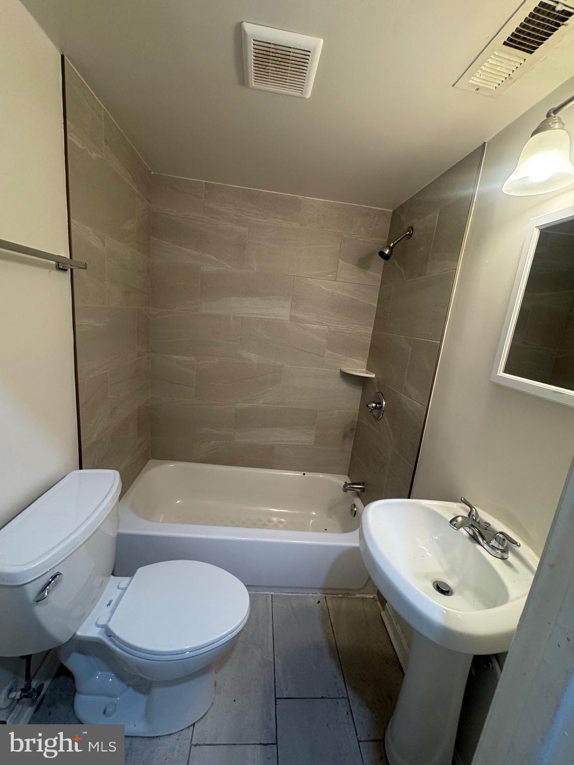 1108 North Bond Street, Unit 1 Baltimore, MD 21213 - Photo 14 of 20 a white toilet sitting next to a bathroom sink and tub