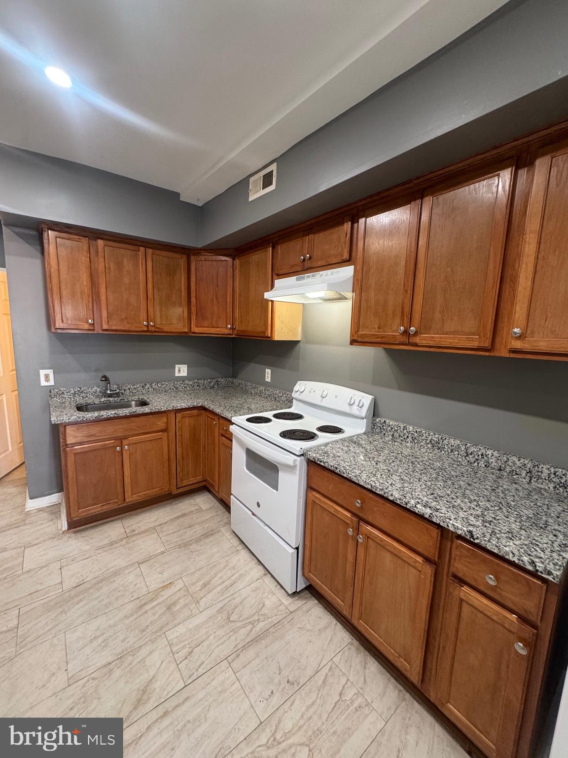 1108 North Bond Street, Unit 1 Baltimore, MD 21213 - Photo 10 of 20 a kitchen with stainless steel appliances granite countertop wooden cabinets a stove a sink and a large window