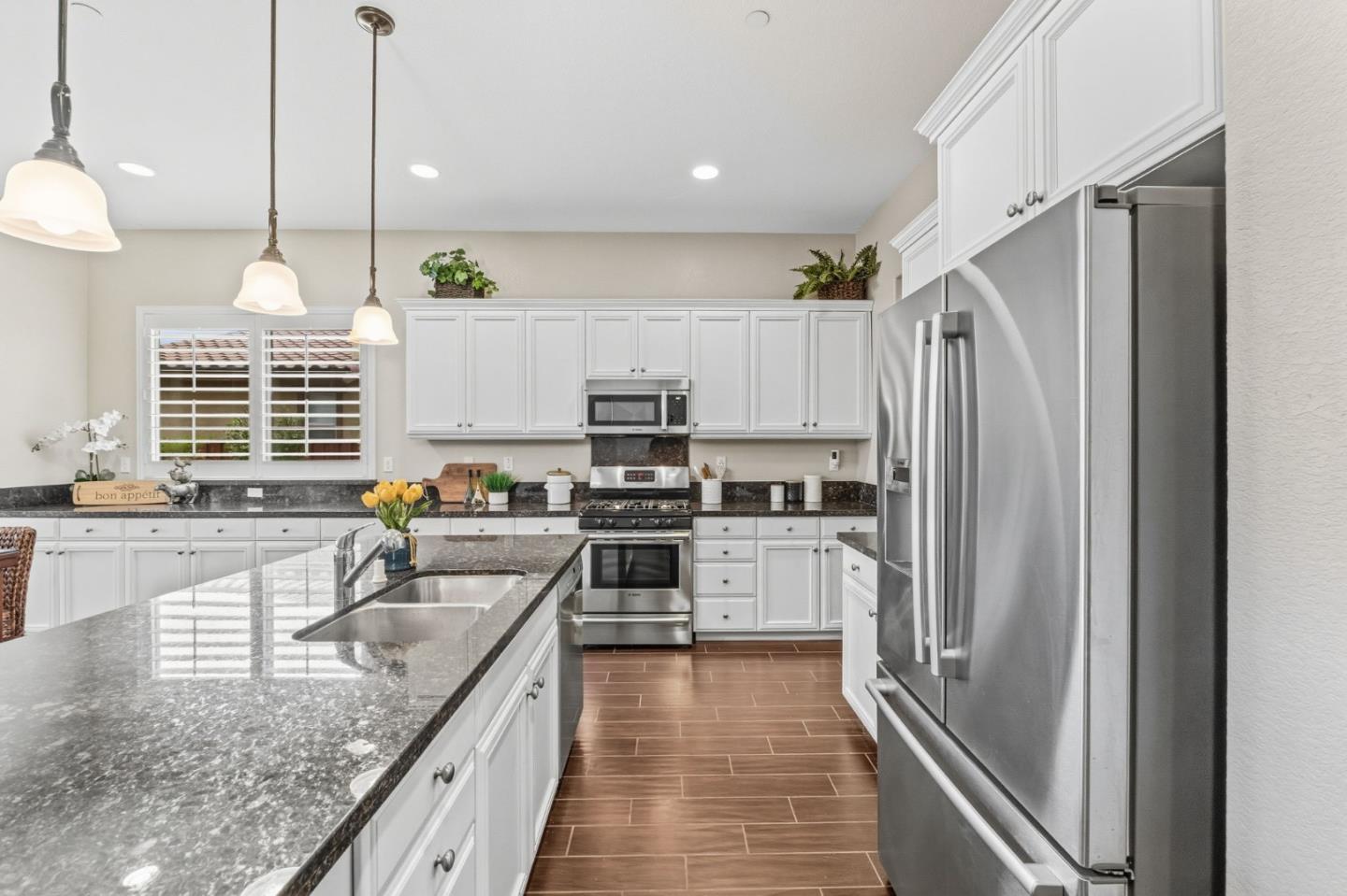 3716 Chiavari Way Manteca, CA 95337 - Photo 13 of 71 a kitchen with a refrigerator a sink and wooden cabinets