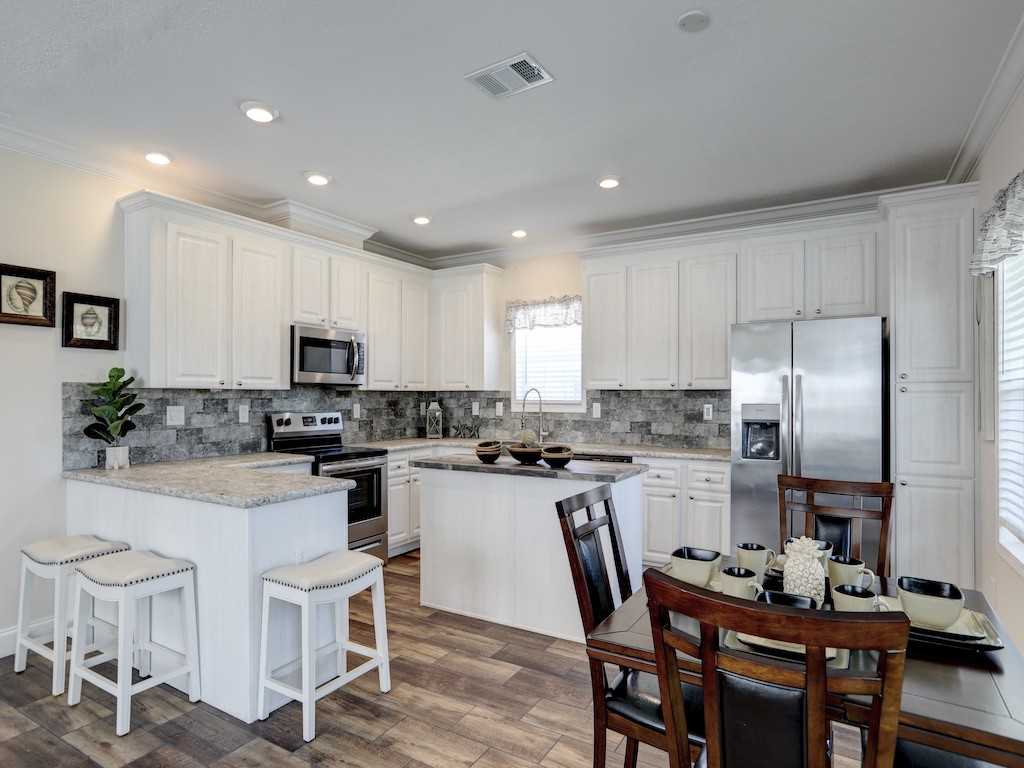 1011 Barefoot Circle Barefoot Bay, FL 32976 - Photo 9 of 31 a kitchen with cabinets a sink dishwasher a stove and chairs with wooden floor