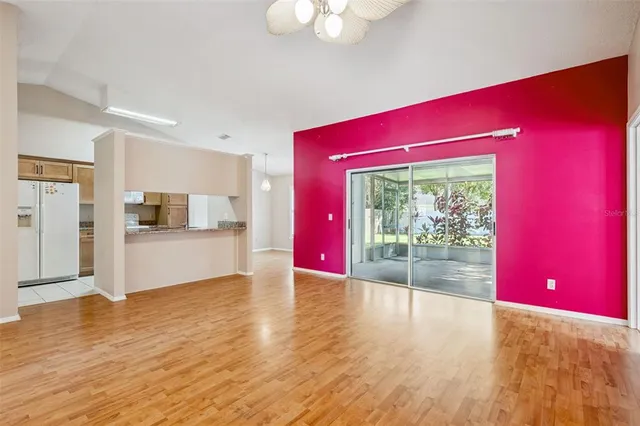a view of empty room with wooden floor and kitchen view