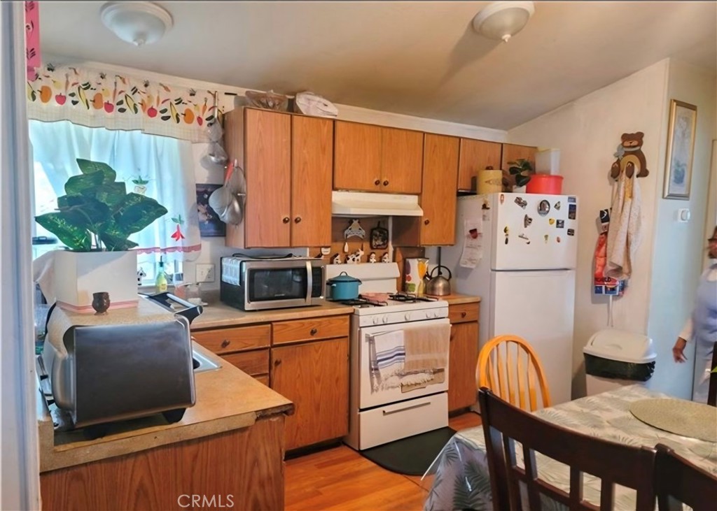 2500 North State Highway 59, Unit 278 Merced, CA 95348 - Photo 10 of 25 a kitchen with stainless steel appliances granite countertop a refrigerator a stove a sink dishwasher and a dining table with wooden floor