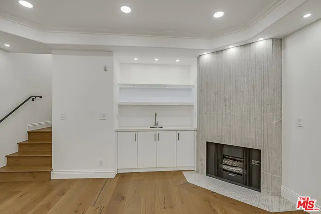 a view of an empty room with wooden floor and a fireplace