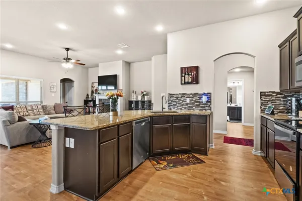 a kitchen with stainless steel appliances granite countertop a stove top oven a sink dishwasher and a refrigerator