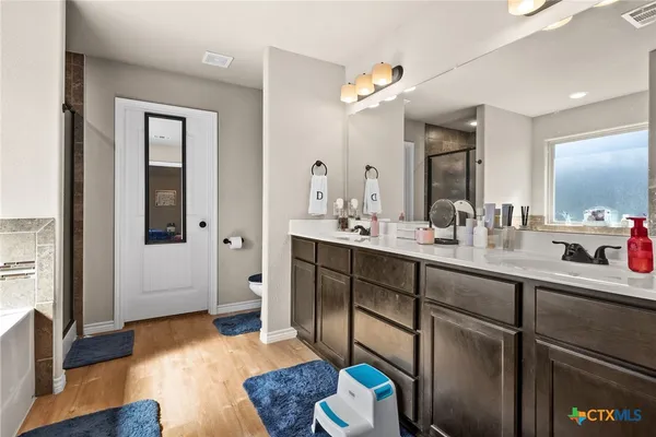 a spacious bathroom with a granite countertop sink a toilet a mirror and shower