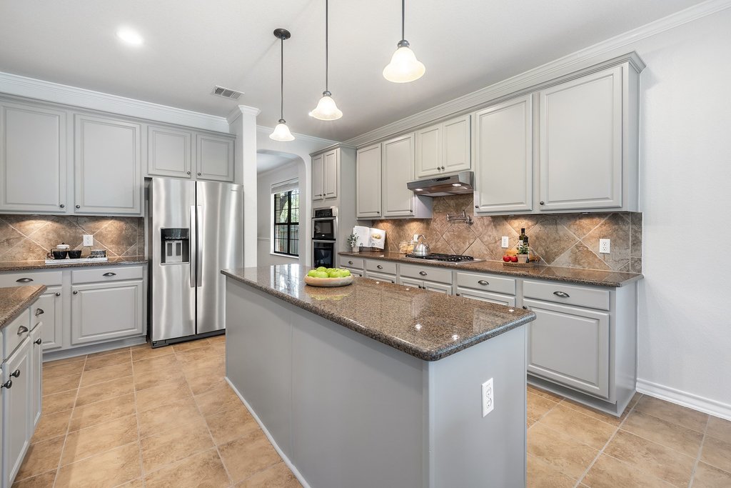 11129 Bastogne Loop Austin, TX 78739 - Photo 11 of 40 The kitchen features abundant cabinets, granite countertops, a large island, breakfast bar seating, gas cooking, double ovens, stainless steel appliances, under-cabinet lighting, and a pot filler at the stove.