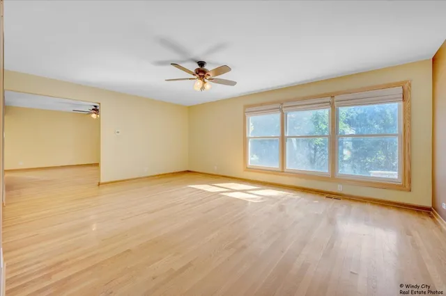 a view of an empty room with a window and wooden floor