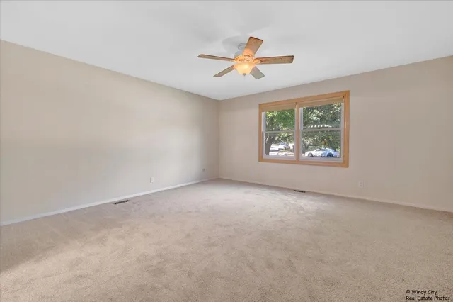 an empty room with windows and fan
