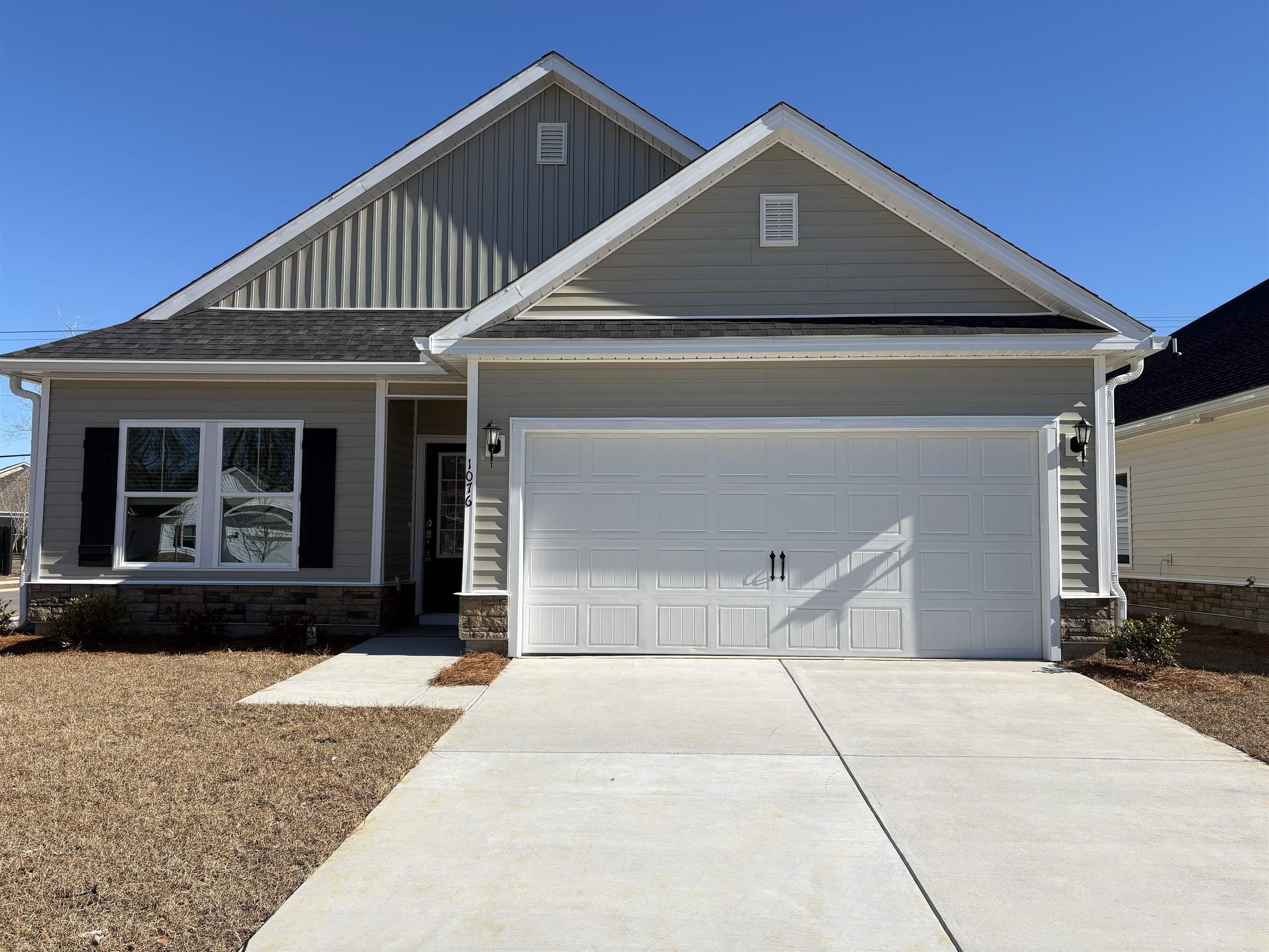 View of front of property with stone siding, board and batten siding, driveway, a garage, and a shingled roof