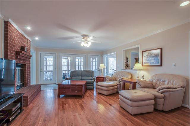 8694 Haselton Road Nashville, TN 37221 - Photo 5 of 19 Living room with brick fireplace with raised hearth and gas logs, ceiling fan, crown molding and hardwood floors.